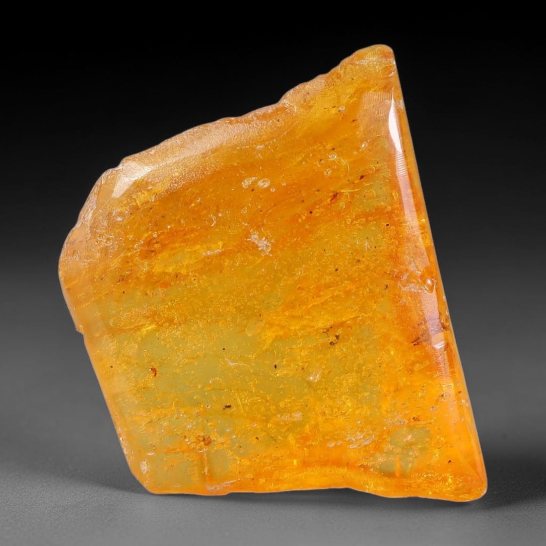 16.92ct Natural Baltic Polished Loose Freeform Amber Gemstone, 55EB: This smoothly polished freeform amber piece carries warm translucent organic clarity with fine natural fossil flecks and tiny mineral inclusions suspended throughout its 25x20mm flowing unstructured s