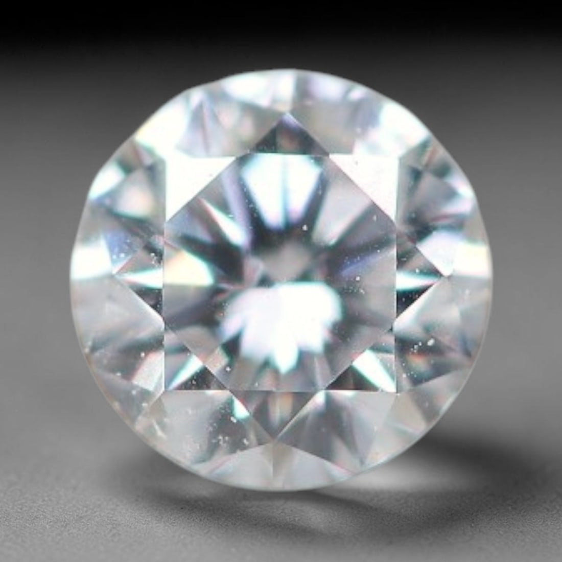 0.12ct Lab-Grown White Round Brilliant HPHT Diamond Loose Gemstone, 77BE: This precision-cut HPHT lab-grown diamond exhibits brilliant colourless transparency, dotted with subtle microscopic growth features within its crystal structure, measured at calibrated dimensions of 