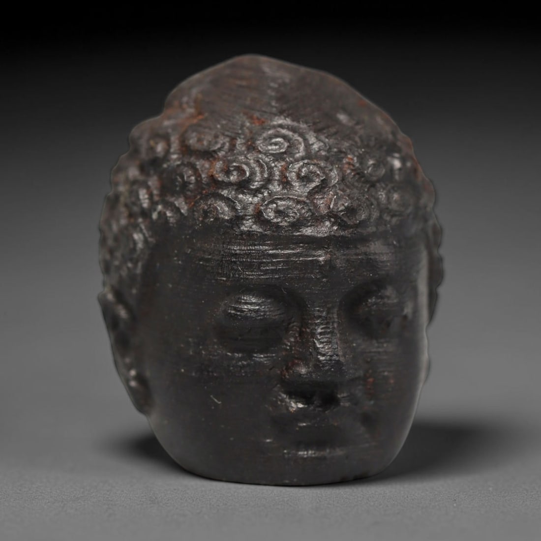 A Chinese Agar Wood Carved Head Art Bead, 40BX: Chinese agar wood head-form art bead measuring 22 x 20 mm. Detailed sculpted facial features cover the exterior surface, with a continuous central bore designed for stringing within beaded strands. Th