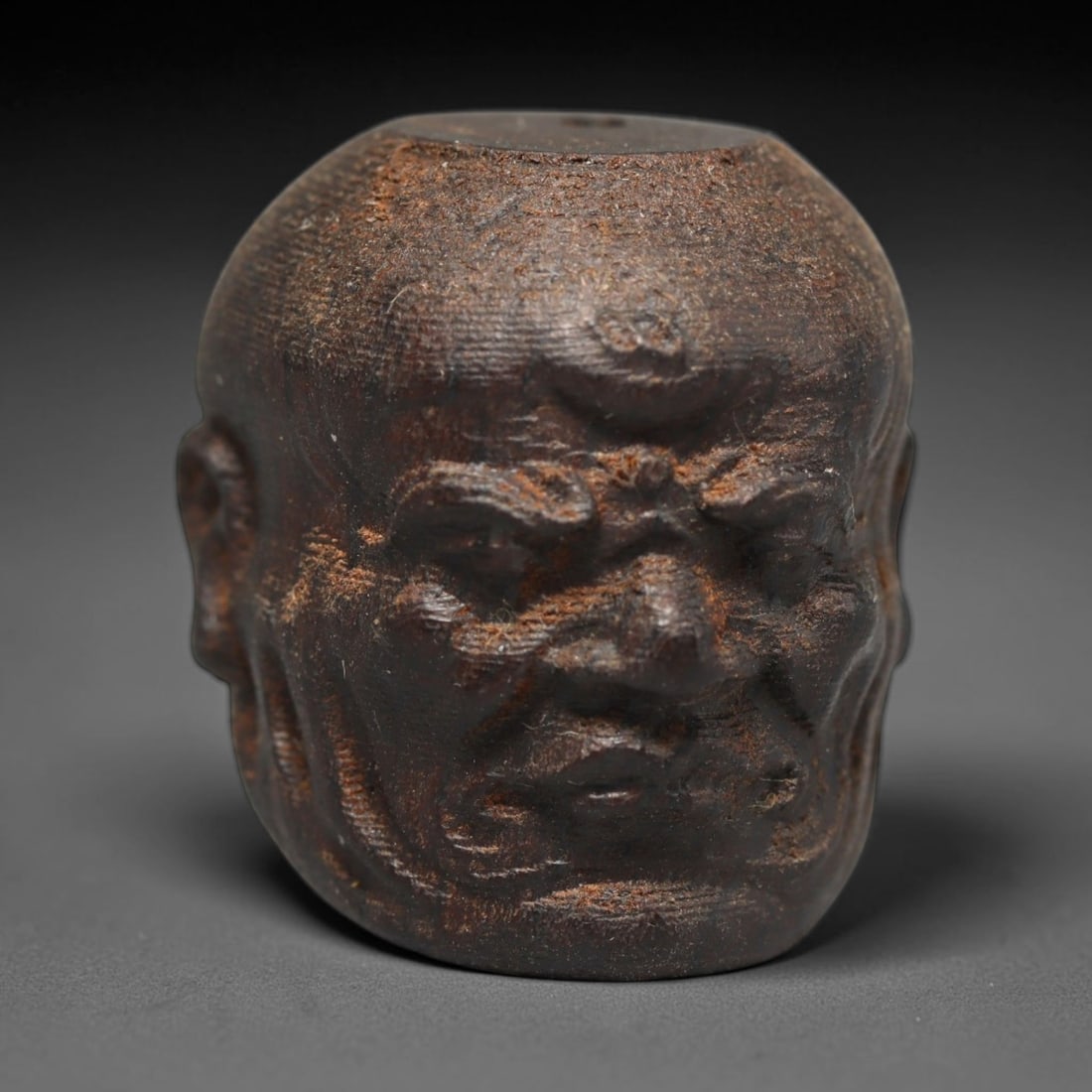 A Chinese Agar Wood Carved Head Art Bead, 38BX: Chinese agar wood head-form art bead measuring 22 x 20 mm. Detailed sculpted facial features cover the exterior surface, with a continuous central bore designed for stringing within beaded strands. Th