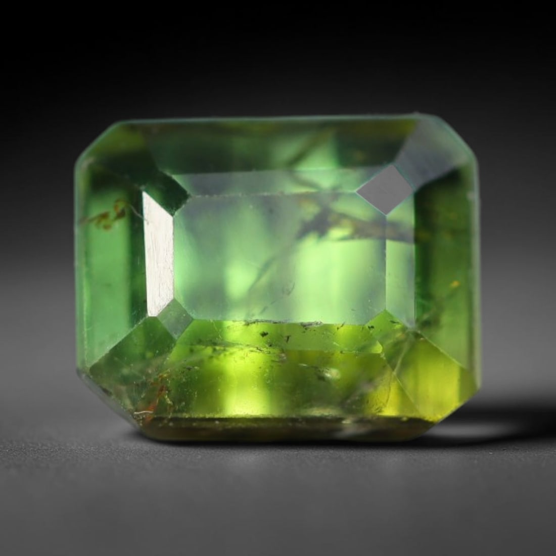 1.56 Carats Natural Mozambique Lime Olive Green Tourmaline Loose Gemstone, 50AK: This transparent Mozambique tourmaline showcases vibrant lime olive green tones, naturally threaded with fine mineral needle inclusions and subtle internal fissures across the crystal body, measuring 