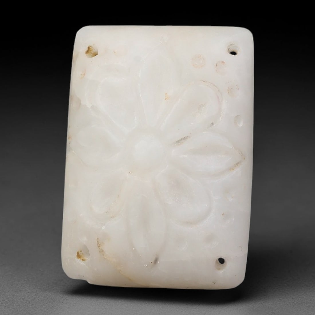 Antique Nishapur Era Silk Road Carved Marble Four-Hole Floral Bead Plaque, 50FL: This antique rectangular bead plaque is carved from marble, originating from the artistic traditions of the Nishapur period along the historic Silk Road. It features raised floral relief detailing alo