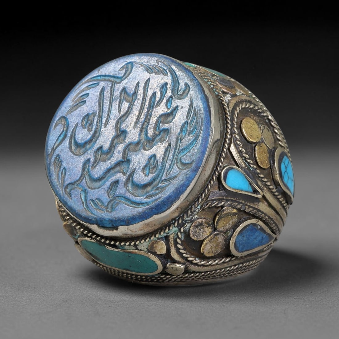 Vintage Islamic Handcrafted Silver Plated Calligraphic Talisman Statement Ring, 8BX: This vintage hand-wrought Islamic statement ring features a central engraved panel bearing traditional calligraphic detailing, set within an ornate silver-plated metal band. The mounting is enriched w