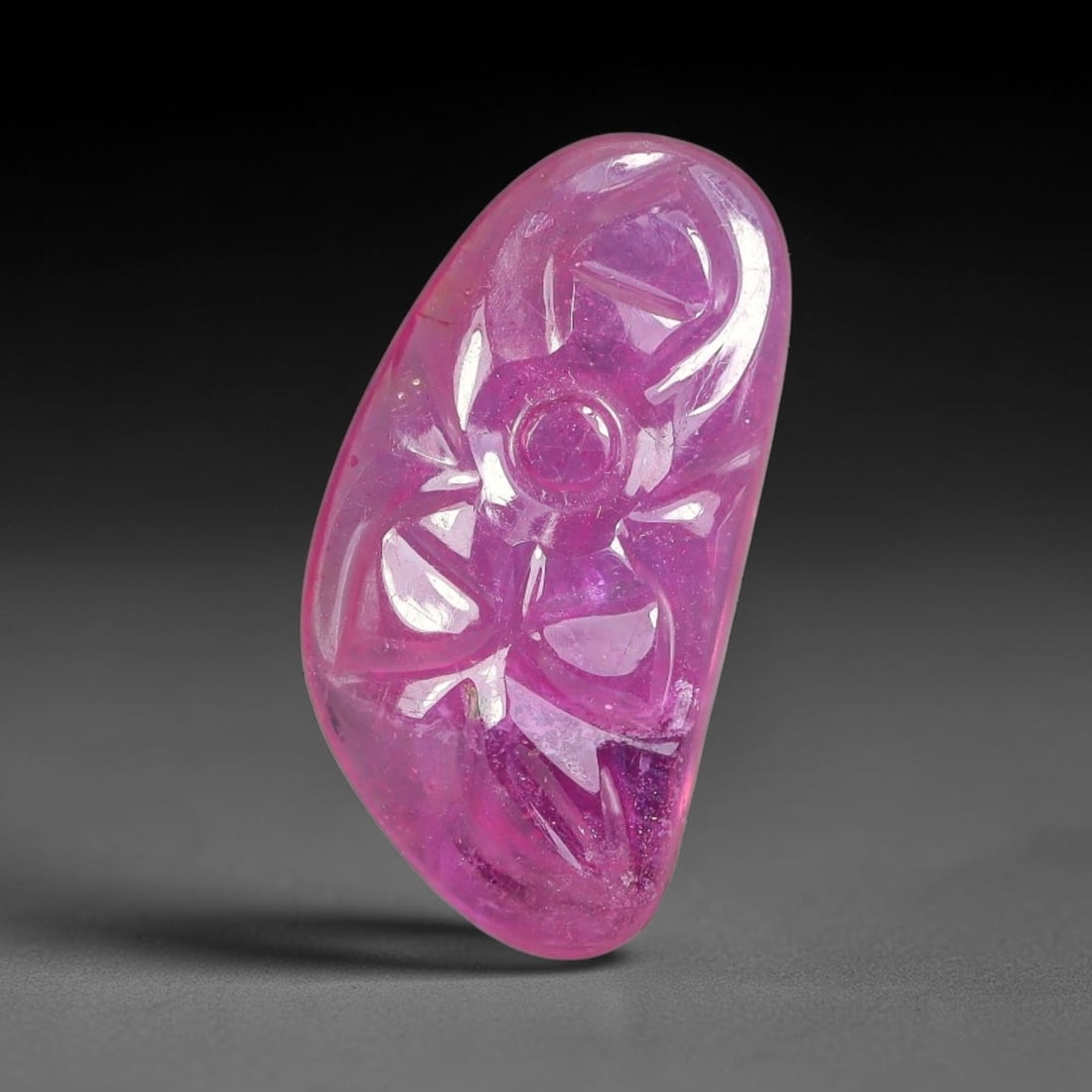 7.73 Carats Natural Mozambique Rich Fuchsia Ruby Loose Gemstone, 58FE: This natural Mozambique ruby cabochon measures 18.2x9.4x3.7mm and features delicate hand engraved floral detailing carved across its polished surface, with a rich saturated fuchsia hue spread evenly t