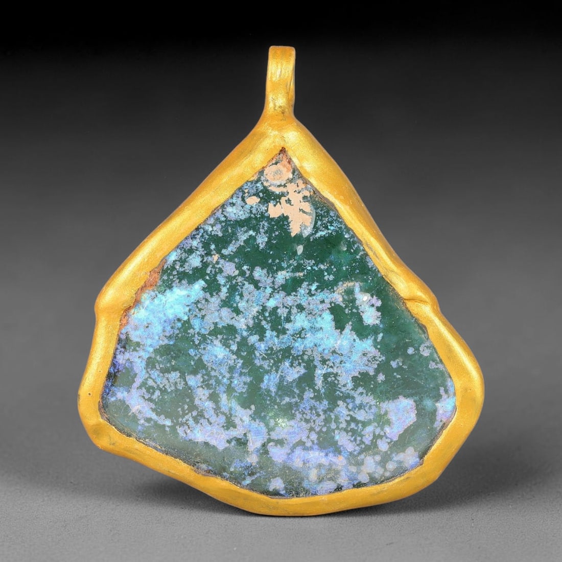 Ancient Roman Glass Slag in Modern Gilt-Edge Pendant, 61FY: This contemporary pendant is crafted from ancient Roman glass slag, featuring a fragmented, iridescent glass surface with weathered patina. The irregular form is bordered by a subtle gilt frame, added