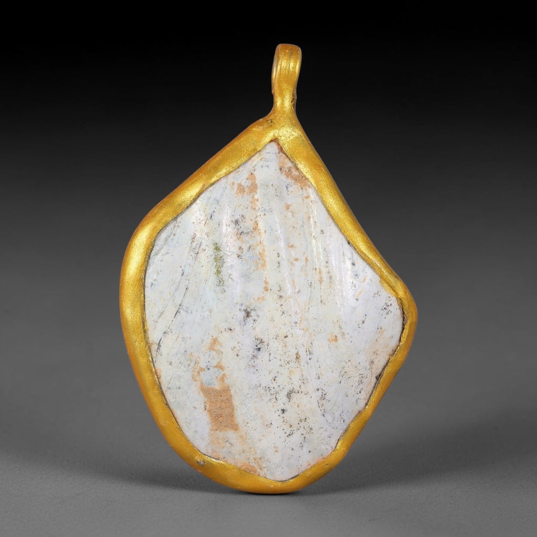 Ancient Roman Glass Slag in Modern Gilt-Edge Pendant, 65FY: This contemporary pendant is crafted from ancient Roman glass slag, featuring a fragmented, iridescent glass surface with weathered patina. The irregular form is bordered by a subtle gilt frame, added