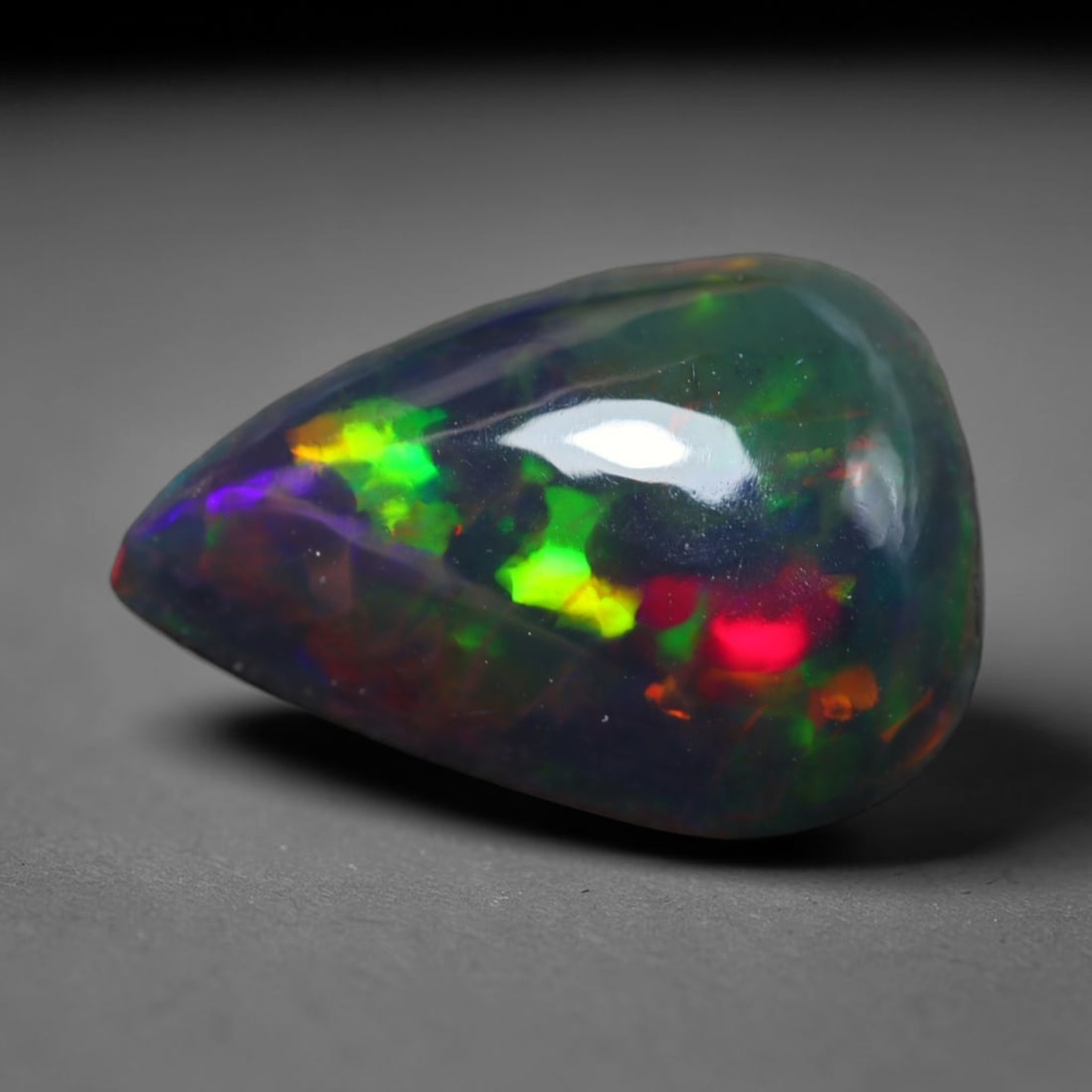 3.00ct Natural Ethiopian Welo Black Smoked Opal Cabochon Loose Gemstone, 56BY: This fully polished Ethiopian Welo opal features a dark smoked base with vivid, sweeping play-of-color shifting across its glossy dome surface, measured at 12x9x5mm. The black smoke treatment deepens 