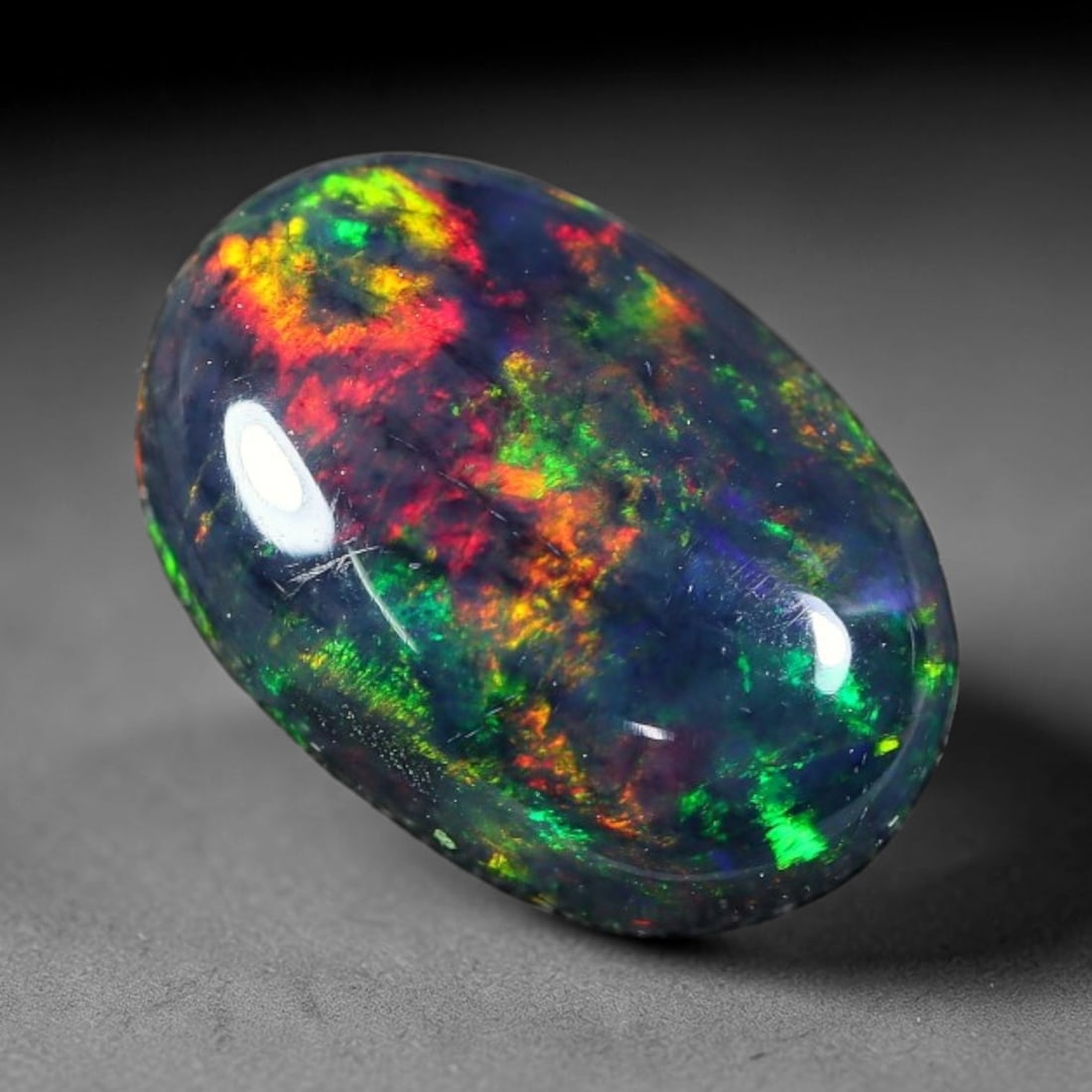 1.82ct Natural Ethiopian Welo Black Smoked Opal Cabochon Loose Gemstone, 45FX: This fully polished Ethiopian Welo opal features a dark smoked base with vivid, sweeping play-of-color shifting across its glossy dome surface, measured at 11x7x4mm. The black smoke treatment deepens 