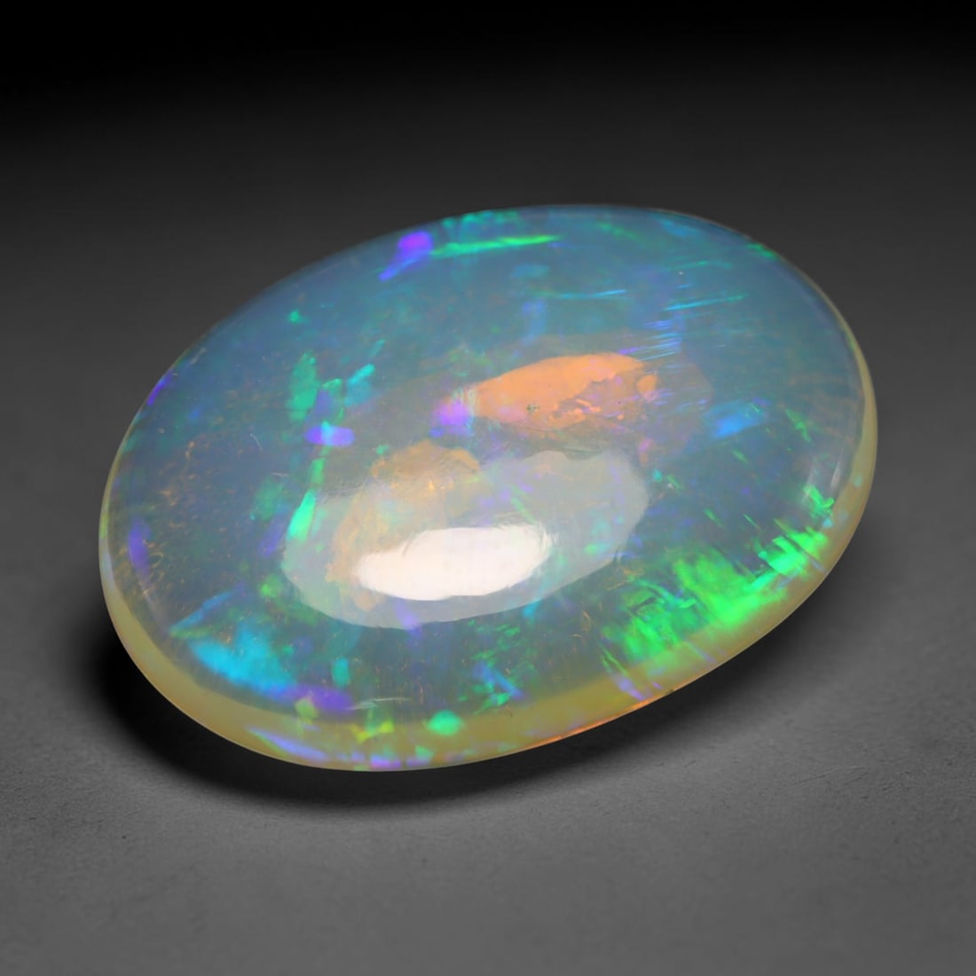 9.36ct Natural Ethiopian Welo Opal Cabochon Loose Gemstone, 70BY: This smoothly polished cabochon is genuine natural Ethiopian Welo opal. The translucent base hosts vivid multi-coloured play-of-colour, displaying dynamic flashes of multi color that shift as the view