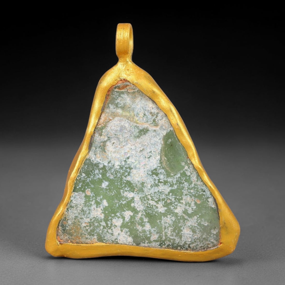 Ancient Roman Glass Slag in Modern Gilt-Edge Pendant, 72FY: This contemporary pendant is crafted from ancient Roman glass slag, featuring a fragmented, iridescent glass surface with weathered patina. The irregular form is bordered by a subtle gilt frame, added