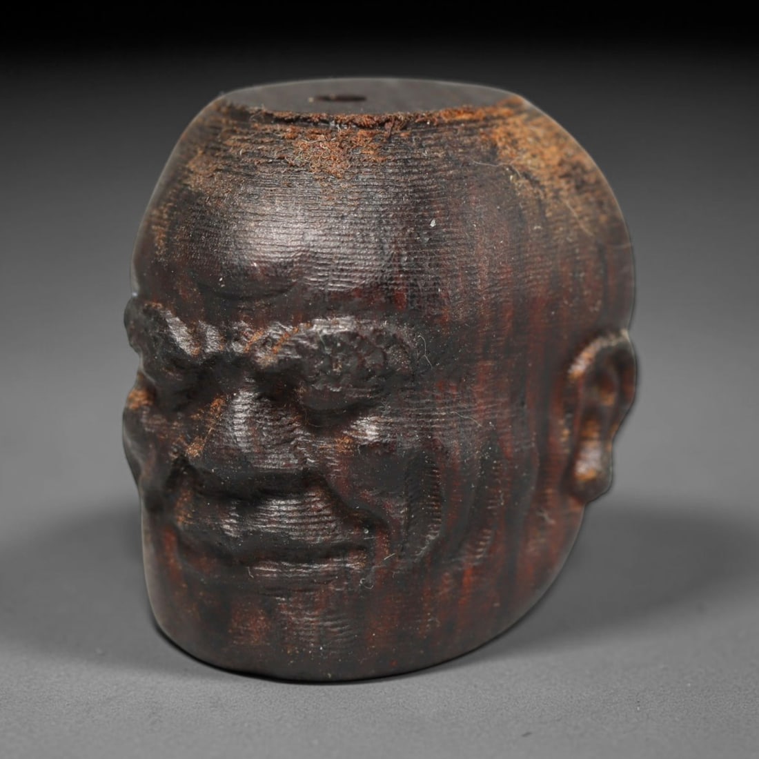 A Chinese Agar Wood Carved Head Art Bead, 28BX: Chinese agar wood head-form art bead measuring 22 x 20 mm. Detailed sculpted facial features cover the exterior surface, with a continuous central bore designed for stringing within beaded strands. Th
