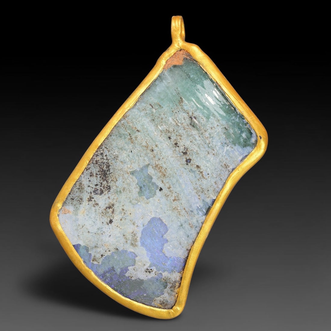 Ancient Roman Glass Slag in Modern Gilt-Edge Pendant, 47FY: This contemporary pendant is crafted from ancient Roman glass slag, featuring a fragmented, iridescent glass surface with weathered patina. The irregular form is bordered by a subtle gilt frame, added