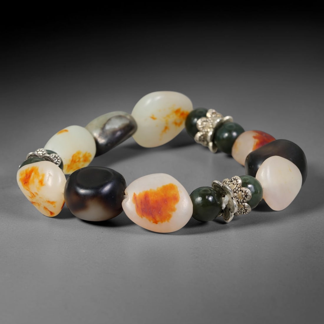 Natural Chinese Hetian Nephrite Jade Tumbled Beaded Bracelet, 30FJ: Features polished natural Chinese Hetian nephrite jade freeform tumbled beads paired with decorative accent elements. Approximate bead size 10mm, arranged into a flexible wearable strand. Each bead ca