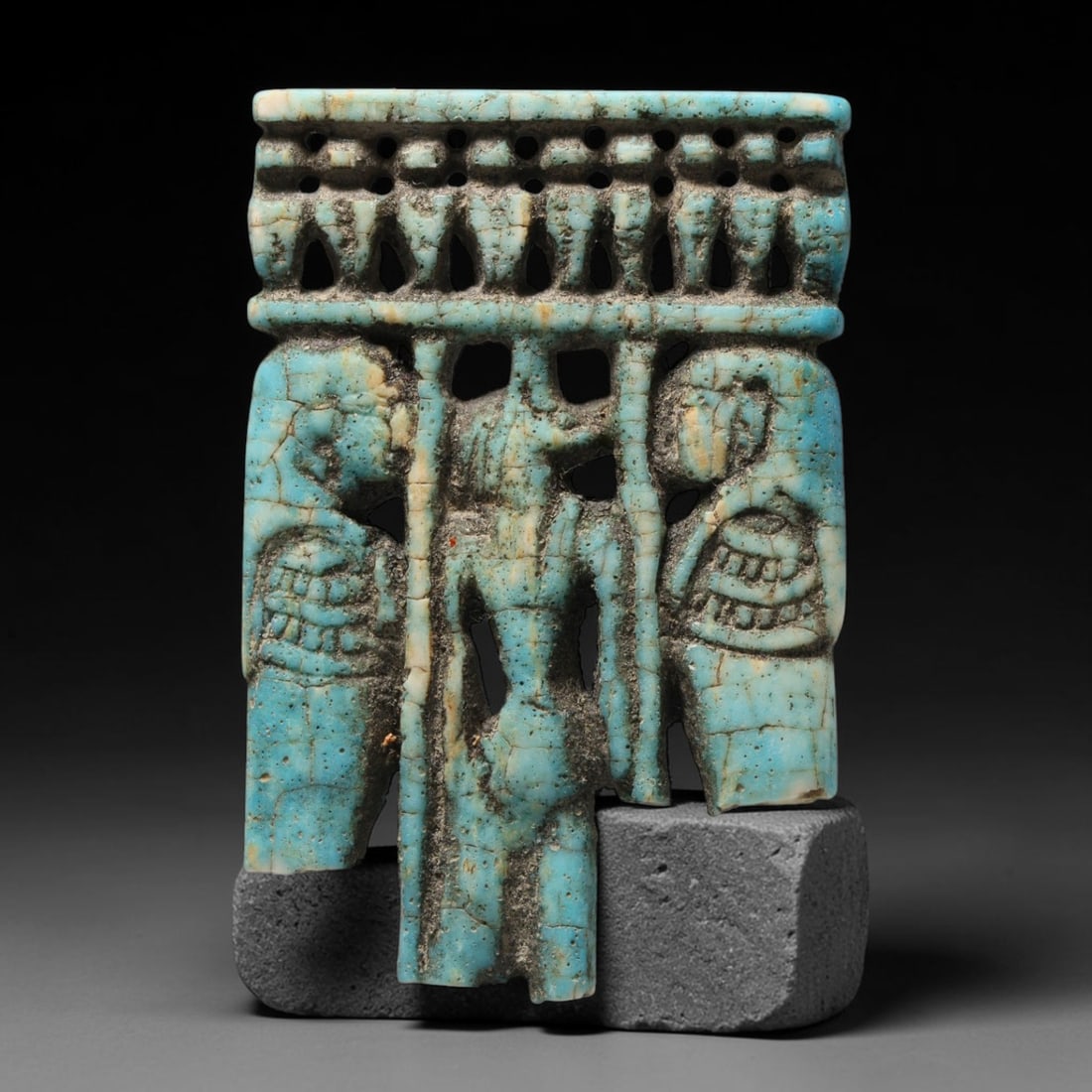 Ancient Egyptian Faience Openwork Figural Plaque Amulet (c.664-332 BCE), 65EC: This pierced decorative amulet is crafted from vibrant blue Egyptian faience with openwork carving, depicting multiple anthropomorphic figures framed beneath an ornate decorative frieze. Extensive age