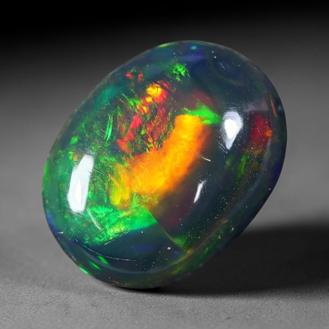 1.92ct Natural Ethiopian Welo Black Smoked Opal Cabochon Loose Gemstone, 62FX: This fully polished Ethiopian Welo opal features a dark smoked base with vivid, sweeping play-of-color shifting across its glossy dome surface, measured at 10x8x4mm. The black smoke treatment deepens 