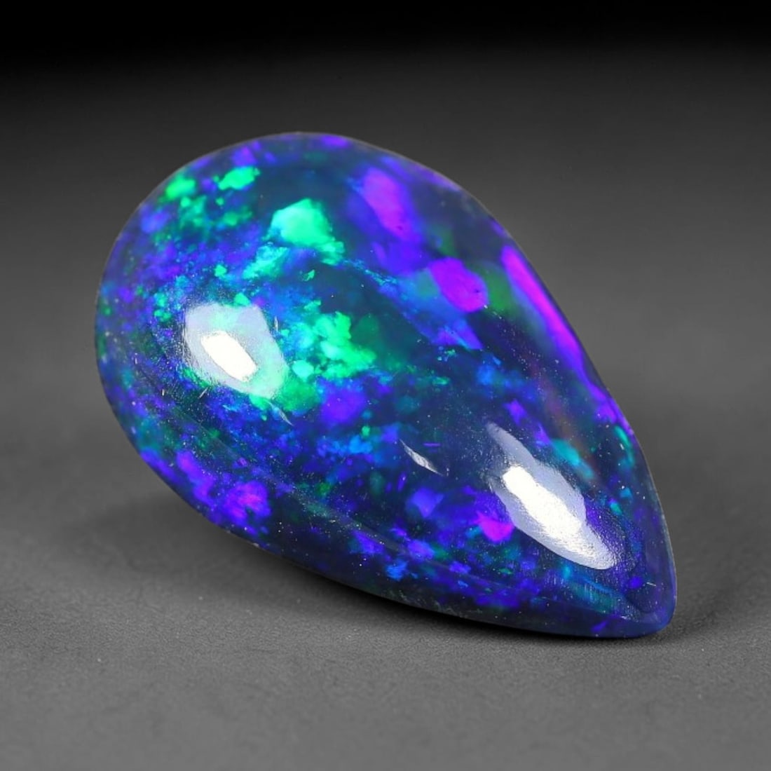 2.09ct Natural Ethiopian Welo Black Smoked Opal Cabochon Loose Gemstone, 9FX: This fully polished Ethiopian Welo opal features a dark smoked base with vivid, sweeping play-of-color shifting across its glossy dome surface, measured at 13x8x4mm. The black smoke treatment deepens 