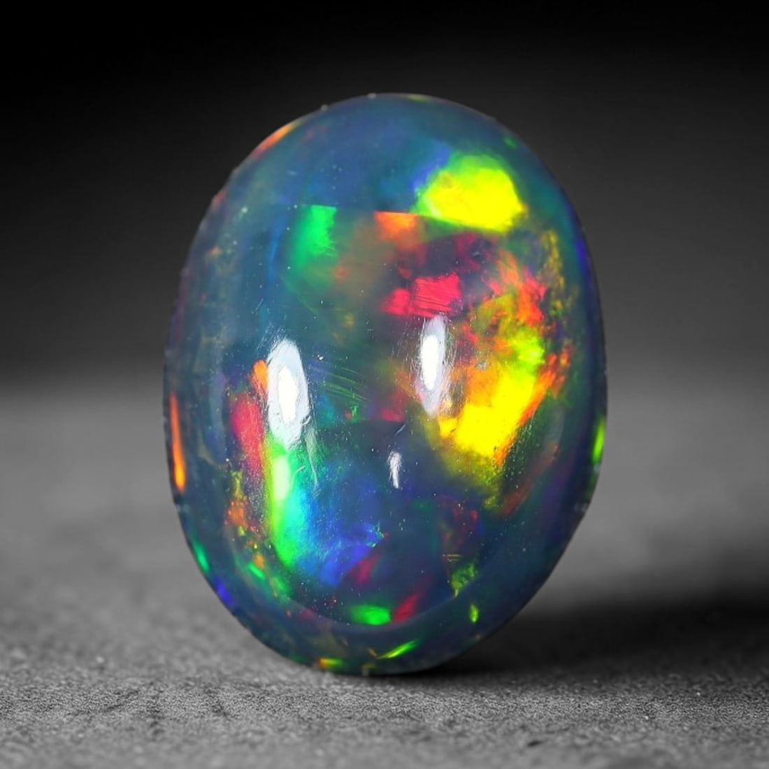 2.04ct Natural Ethiopian Welo Black Smoked Opal Cabochon Loose Gemstone, 49FX: This fully polished Ethiopian Welo opal features a dark smoked base with vivid, sweeping play-of-color shifting across its glossy dome surface, measured at 11x8x4mm. The black smoke treatment deepens 