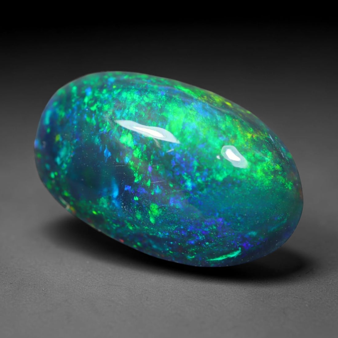 2.29ct Natural Ethiopian Welo Black Smoked Opal Cabochon Loose Gemstone, 33FL: This fully polished Ethiopian Welo opal features a dark smoked base with vivid, sweeping play-of-color shifting across its glossy dome surface, measured at 12x7.4x5mm. The black smoke treatment deepen
