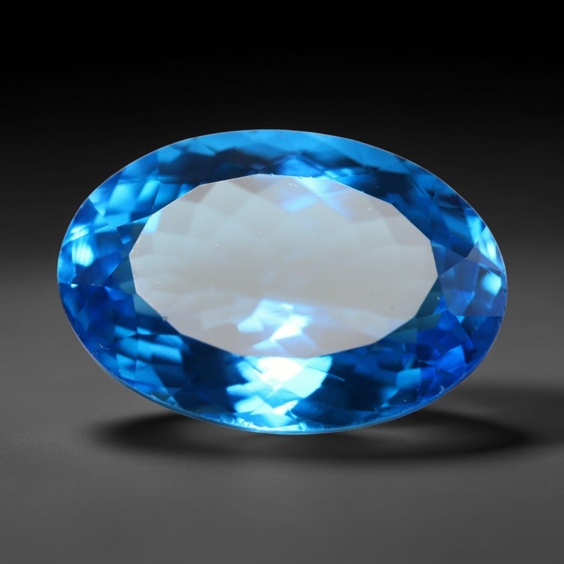 19.16ct Natural Brazilian London Blue Topaz Oval Faceted Loose Gemstone, 87BZ: This precisely cut oval faceted gemstone is natural London Blue Topaz originating from Brazil. The stone showcases an intense, rich deep royal blue hue, complemented by crisp, symmetrical faceting tha