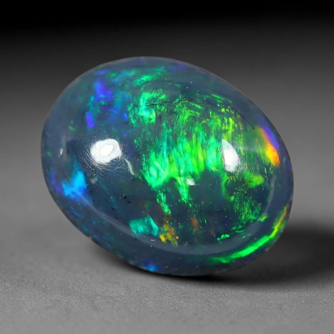 2.50ct Natural Ethiopian Welo Black Smoked Opal Cabochon Loose Gemstone, 21FX: This fully polished Ethiopian Welo opal features a dark smoked base with vivid, sweeping play-of-color shifting across its glossy dome surface, measured at 11x8x5mm. The black smoke treatment deepens 