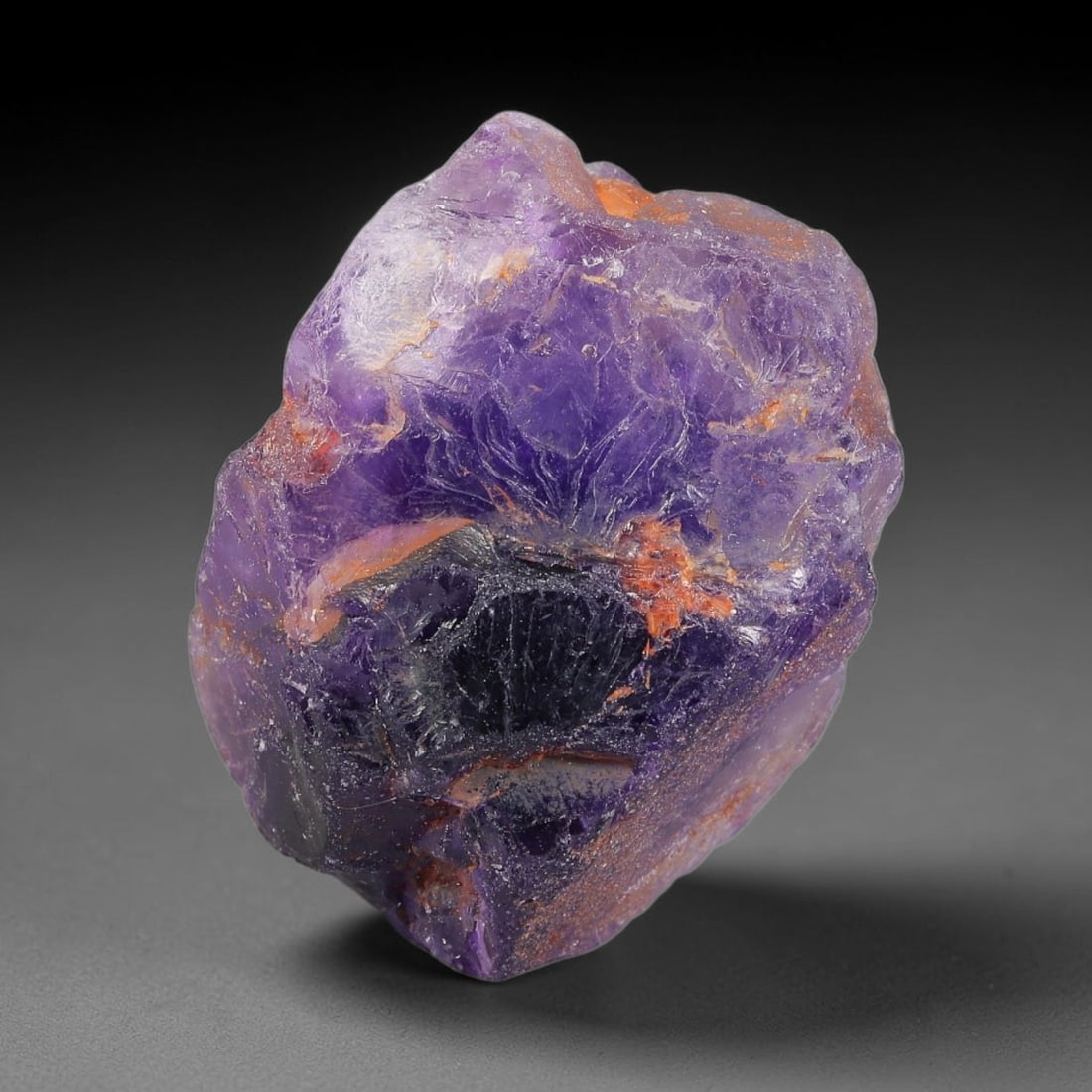 129ct Natural Chinese Deep Violet Purple Fluorite Rough, 4AT: This rugged fluorite rough boasts rich layered violet purple saturation blended with warm rust-colored mineral inclusions that streak its uneven raw surface, soft translucency lets light drift through