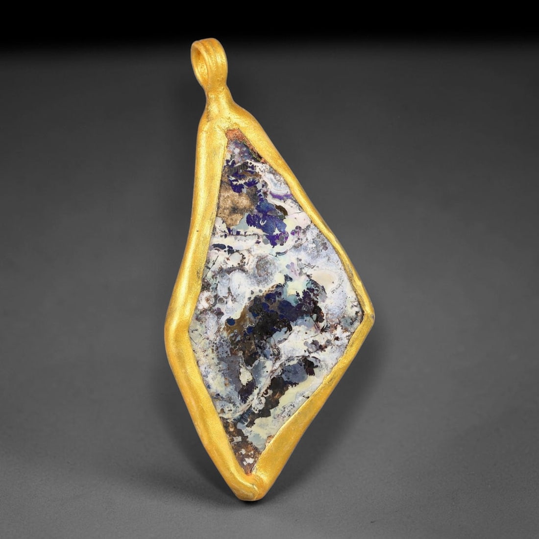 Ancient Roman Glass Slag in Modern Gilt-Edge Pendant, 69FY: This contemporary pendant is crafted from ancient Roman glass slag, featuring a fragmented, iridescent glass surface with weathered patina. The irregular form is bordered by a subtle gilt frame, added