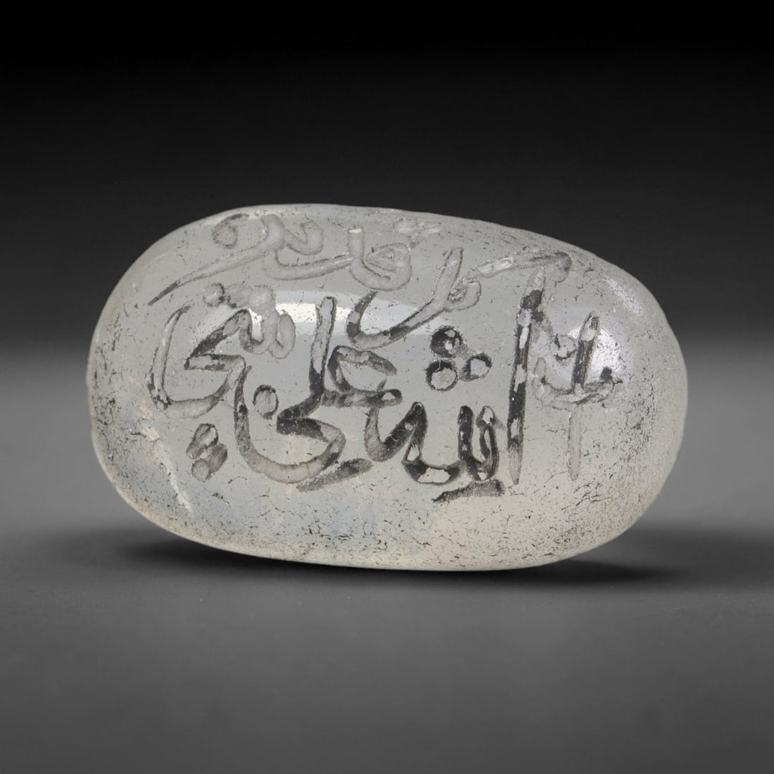 Early Vintage Islamic White Glass Calligraphic Intaglio Seal Cabochon (Post 1900 CE), 77BX: This early vintage glass intaglio seal cabochon draws from enduring Islamic seal-making traditions, formed from translucent pale glass with a smoothly rounded polished surface. The face features caref