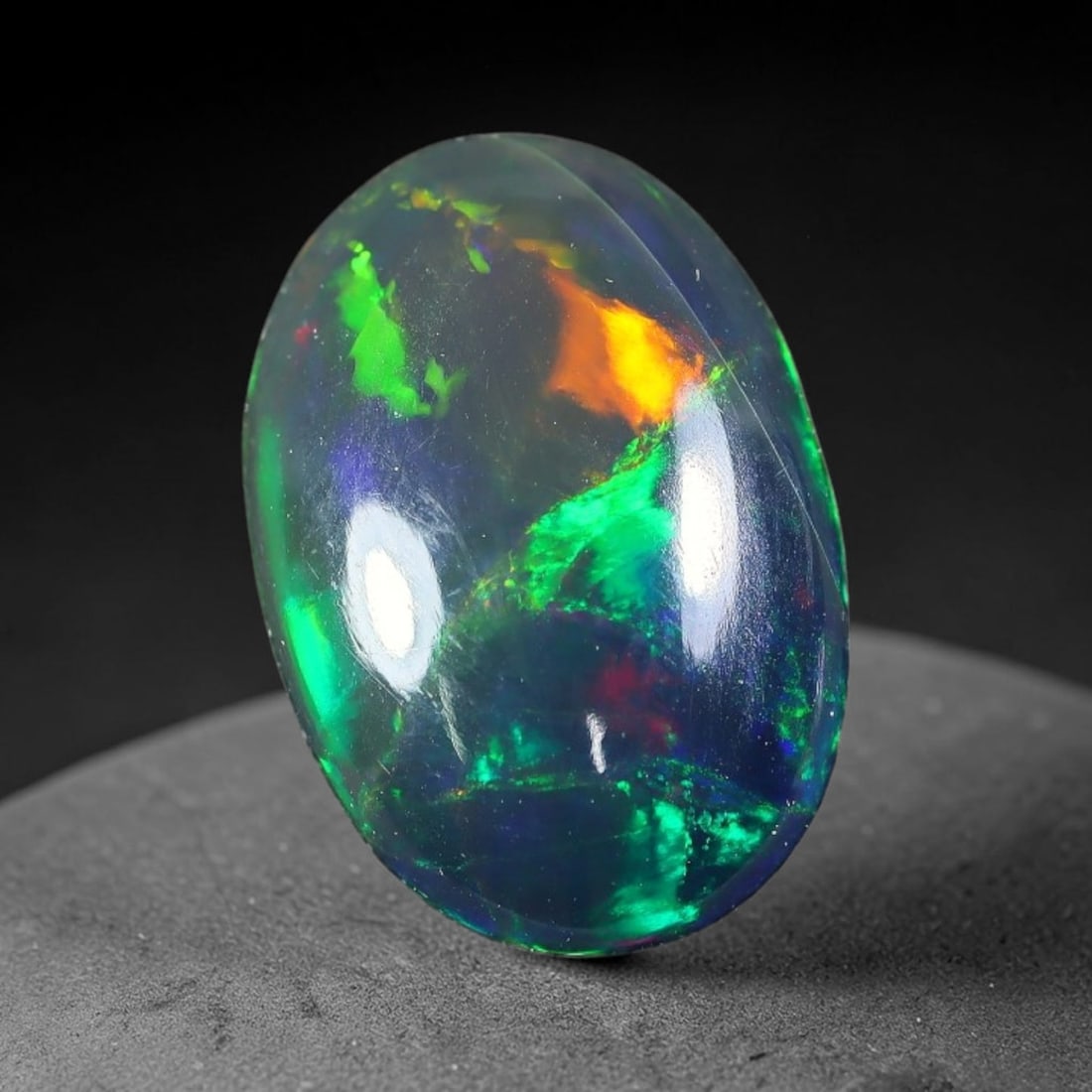 1.50ct Natural Ethiopian Welo Black Smoked Opal Cabochon Loose Gemstone, 46FX: This fully polished Ethiopian Welo opal features a dark smoked base with vivid, sweeping play-of-color shifting across its glossy dome surface, measured at 12x8x3mm. The black smoke treatment deepens 