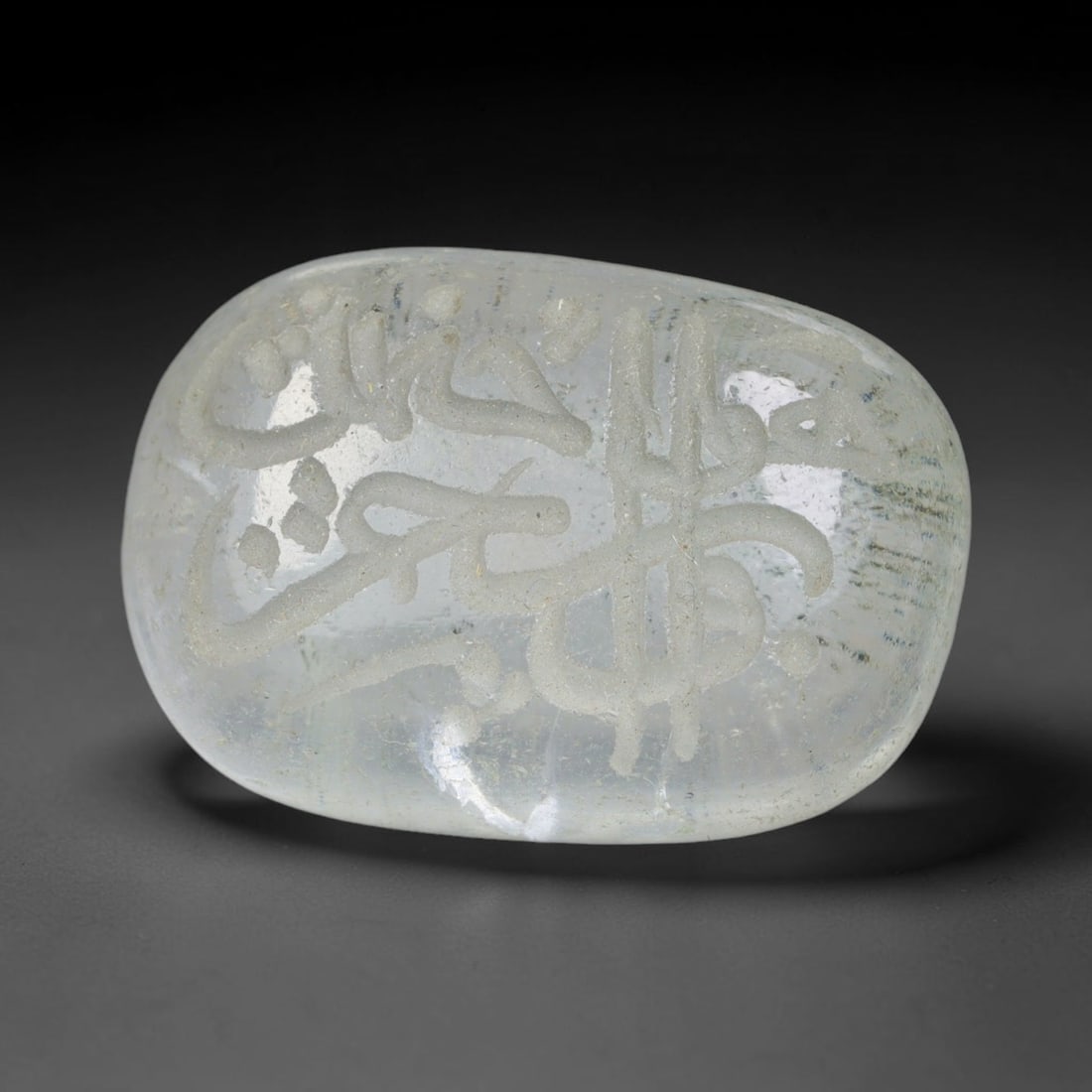 Early Vintage Islamic White Glass Calligraphic Intaglio Seal Cabochon (Post 1900 CE), 79BX: This early vintage glass intaglio seal cabochon draws from enduring Islamic seal-making traditions, formed from translucent pale glass with a smoothly rounded polished surface. The face features caref