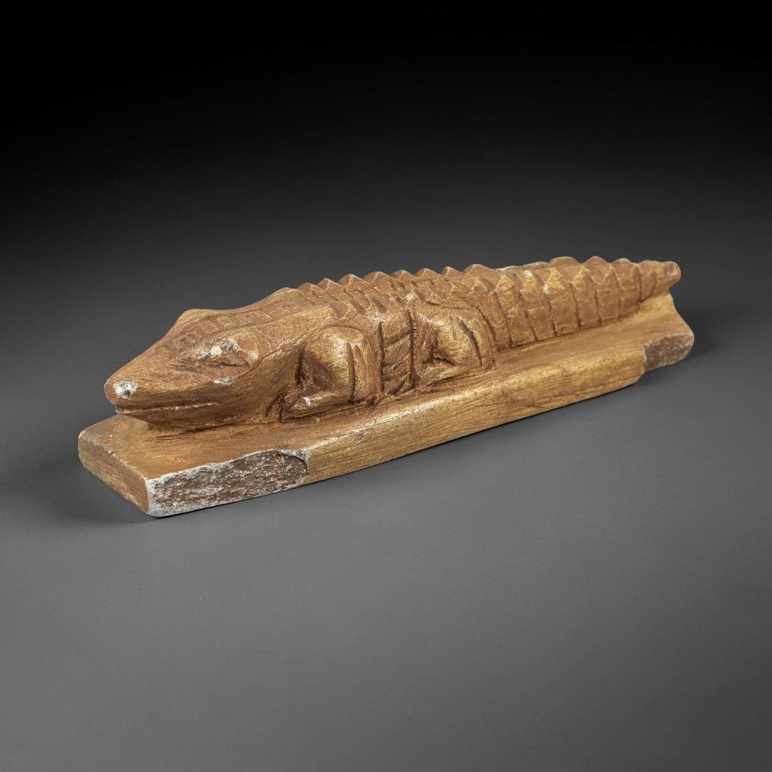 Ancient Medieval Egyptian Carved Limestone Recumbent Crocodile Talisman (641-1500 CE), 94AL: Elongated hand-carved limestone amulet depicting a resting crocodile mounted upon a flat rectangular base. Deep incised linear detailing renders segmented dorsal scutes, simplified limbs, facial featu