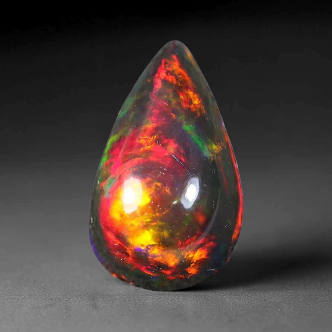 3.40ct Natural Ethiopian Welo Black Smoked Opal Cabochon Loose Gemstone, 12FX: This fully polished Ethiopian Welo opal features a dark smoked base with vivid, sweeping play-of-color shifting across its glossy dome surface, measured at 14x8x6mm. The black smoke treatment deepens 