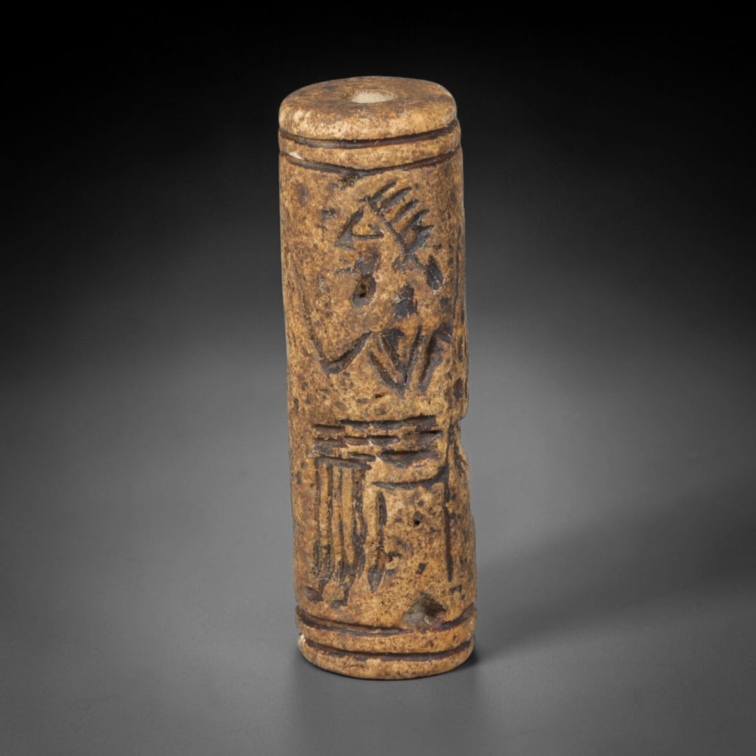 Ancient Mesopotamian Stone Cylinder Seal (c.2300-539 BCE), 68EF: This carved pale weathered stone cylinder seal originates from Ancient Mesopotamia. The cylindrical body features continuous incised imagery encircling the surface, framed by simple horizontal border 