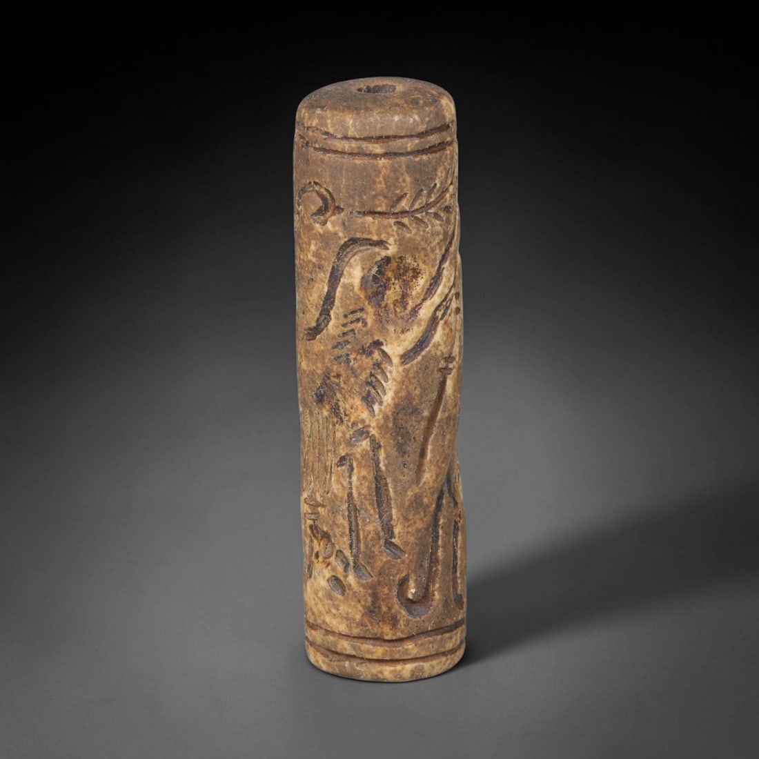 Ancient Mesopotamian Stone Cylinder Seal (c.2300-539 BCE), 46ED: This carved pale weathered stone cylinder seal originates from Ancient Mesopotamia. The cylindrical body features continuous incised imagery encircling the surface, framed by simple horizontal border 