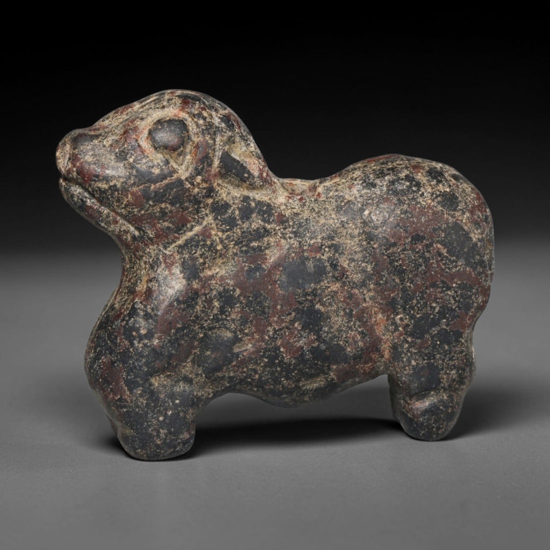 Ancient Sasanian Persian Zoomorphic Stone Amulet (c.224-651 CE), 16ED: This dark mottled stone zoomorphic amulet originates from Ancient Sasanian Persian culture. Sculpted as a standing quadruped with defined facial detailing, the compact form bears natural variegated mi
