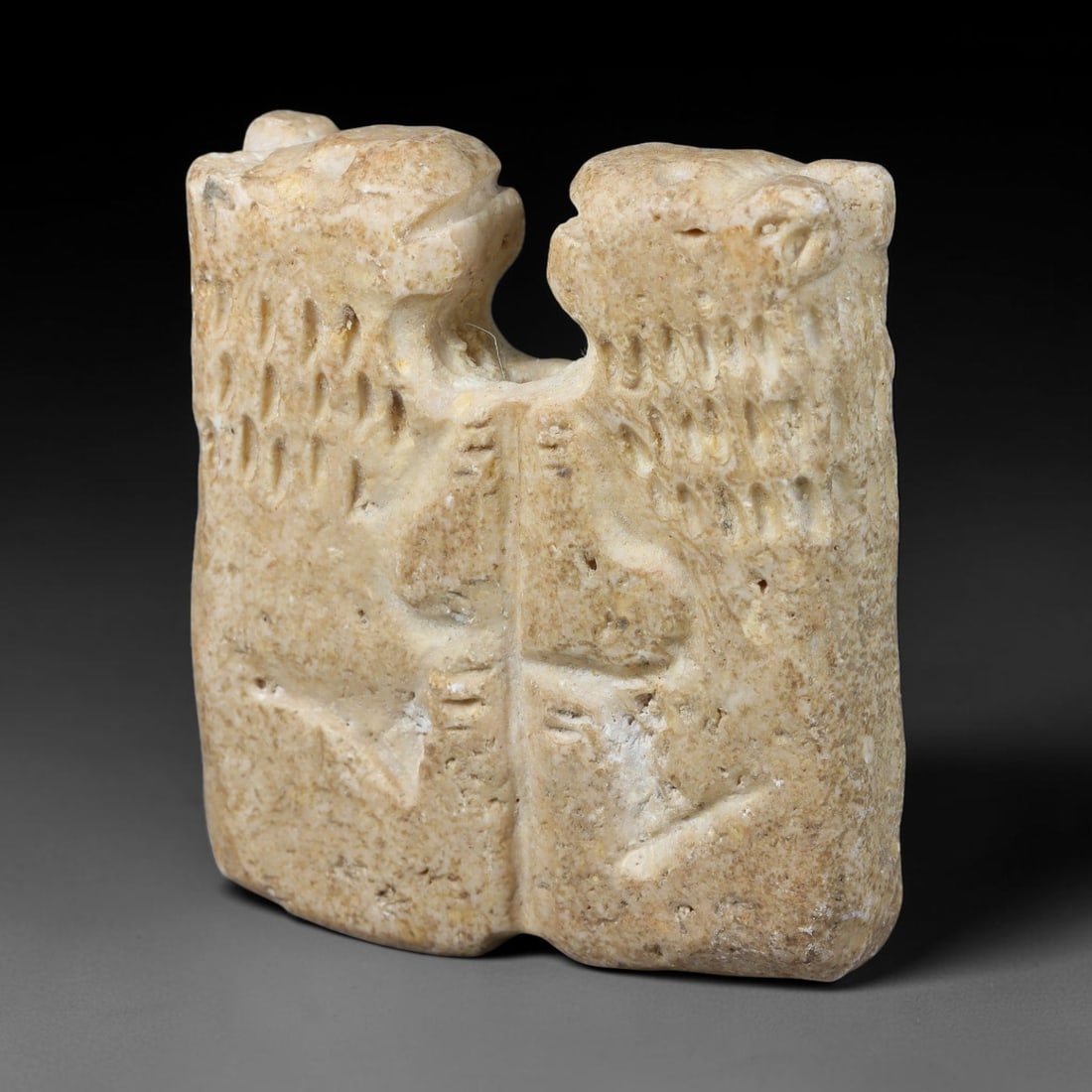 Ancient Syro-Hittite Limestone Twin Feline Amulet Plaque (1200-800 BCE), 18EF: This carved limestone amulet plaque originates from Iron Age Syro-Hittite cultures of Northern Syria and Eastern Anatolia. The relief depicts a pair of confronting felines with incised linear detailin