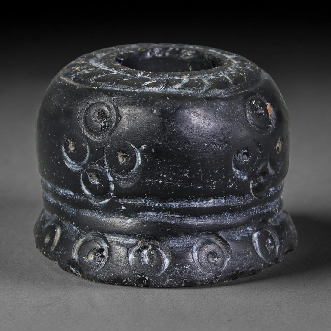 Ancient Iron Age Levantine Jet Stone Barrel Amulet Bead (1200-600 BCE), 74EF: This barrel-form perforated amulet bead is carved from polished jet stone, originating from Iron Age Levantine cultures of the ancient Near East. The surface is adorned with deeply incised concentric 