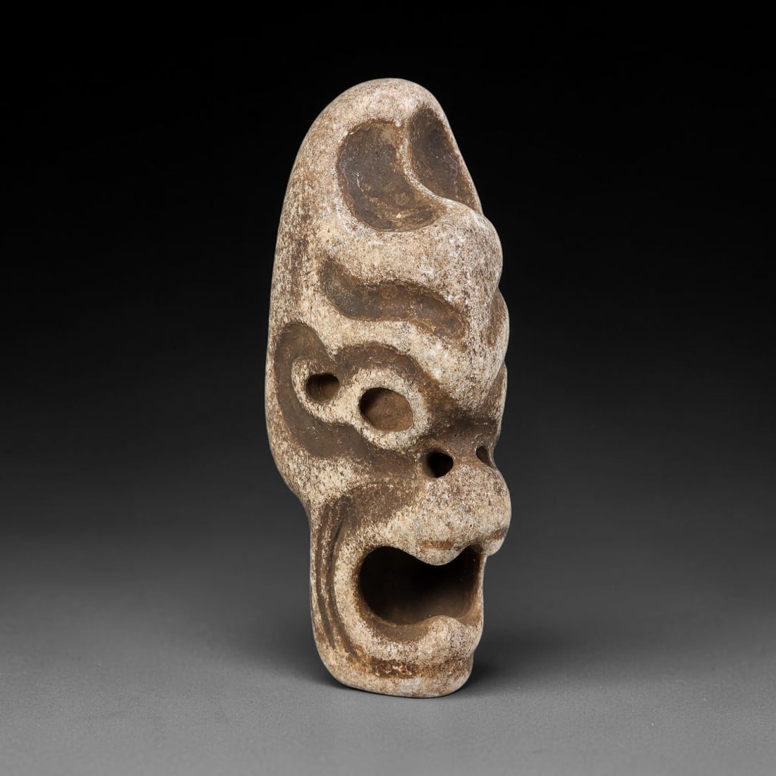 Ancient Medieval Himalayan Tribal Naga Stone Demon Mask Talisman (8th-14th Centuries CE), 27EF: This carved miniature mask amulet is crafted from pale weathered stone, originating from Himalayan Tribal Naga cultural traditions. The artefact depicts a fierce open-mouthed demonic face with deep re