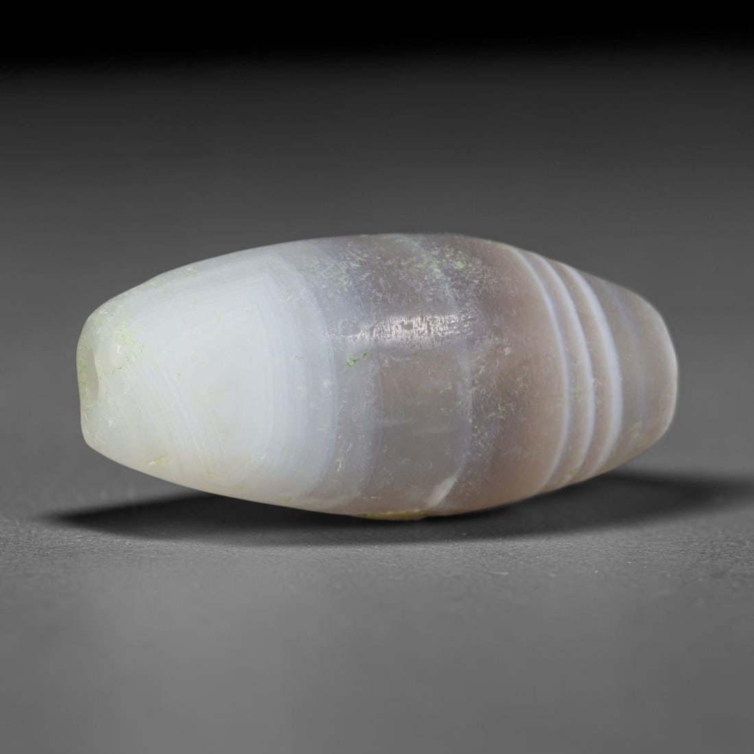 Ancient Eastern Han Dynasty Layered Taupe Banded Agate Barrel Bead (25-220 CE), 63AD: This antique banded agate barrel bead originates from China's Eastern Han Dynasty, a flourishing era of Silk Road exchange where Chinese lapidaries crafted polished agate talismans for domestic aristo