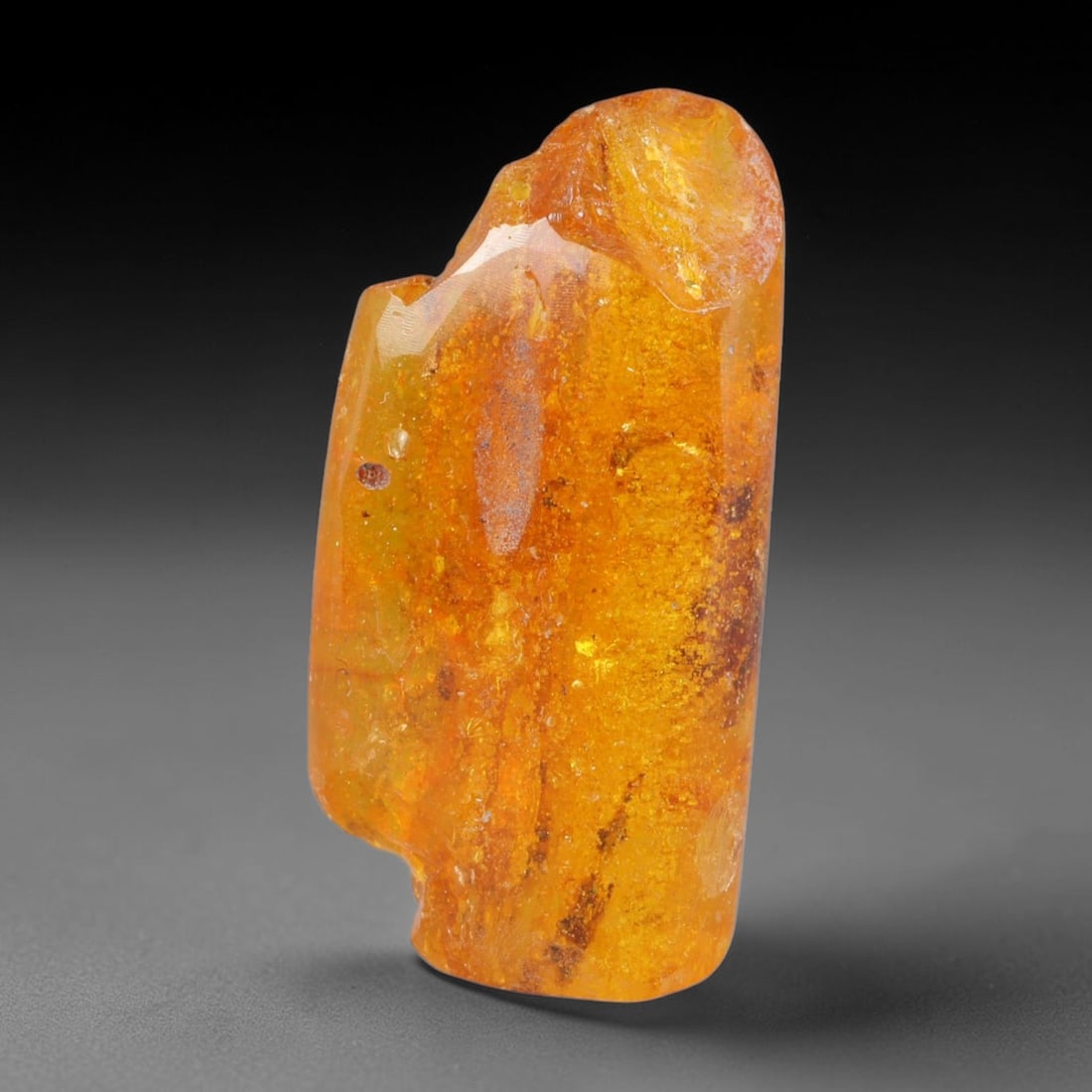 17.61ct Natural Baltic Polished Loose Freeform Amber Gemstone, 59AT: This smoothly polished freeform amber piece carries warm translucent organic clarity with fine natural fossil flecks and tiny mineral inclusions suspended throughout its 33x16mm flowing unstructured s