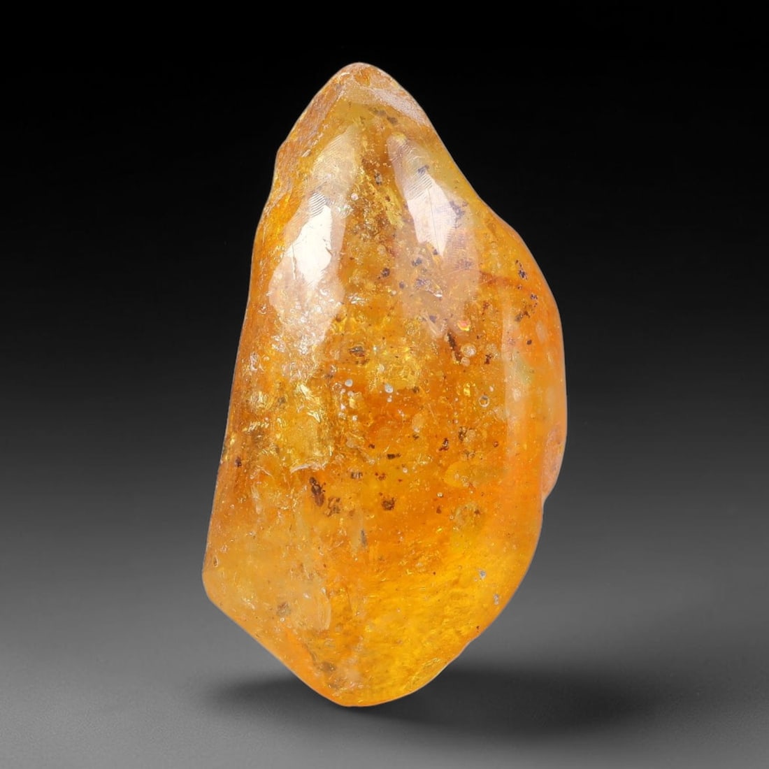 15.25ct Natural Baltic Polished Loose Freeform Amber Gemstone, 31EB: This smoothly polished freeform amber piece carries warm translucent organic clarity with fine natural fossil flecks and tiny mineral inclusions suspended throughout its 32x17mm flowing unstructured s