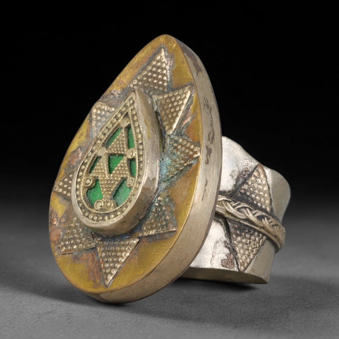 Antique Central Asian Mixed Metal Green Enamel Star Motif Statement Ring, 68AA: Vintage antique nomadic tribal ring crafted from mixed silvered and brass-toned metal, featuring an oversized teardrop ring face measuring 3.5cm x 2.4cm. The ornate front displays an eight-pointed sta