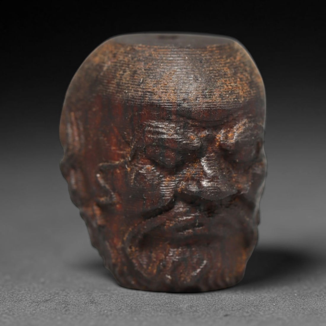 A Chinese Agar Wood Carved Head Art Bead, 22BX: Chinese agar wood head-form art bead measuring 22 x 20 mm. Detailed sculpted facial features cover the exterior surface, with a continuous central bore designed for stringing within beaded strands. Th