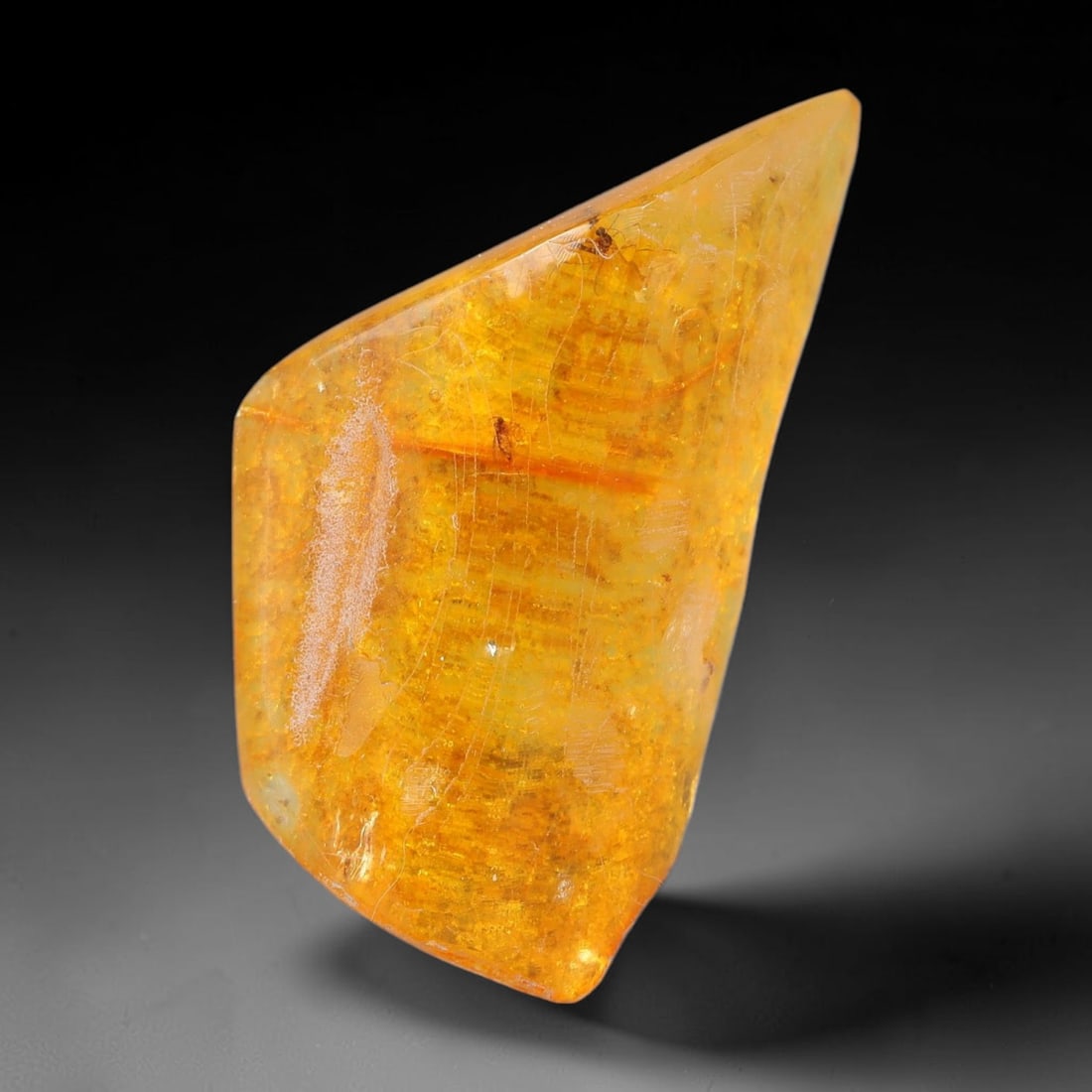 16.94ct Natural Baltic Polished Loose Freeform Amber Gemstone, 73AT: This smoothly polished freeform amber piece carries warm translucent organic clarity with fine natural fossil flecks and tiny mineral inclusions suspended throughout its 36x21mm flowing unstructured s