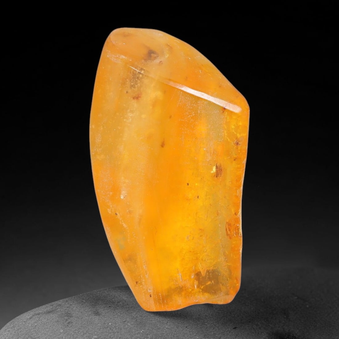 13.83ct Natural Baltic Polished Loose Freeform Amber Gemstone, 26EB: This smoothly polished freeform amber piece carries warm translucent organic clarity with fine natural fossil flecks and tiny mineral inclusions suspended throughout its 29x17mm flowing unstructured s