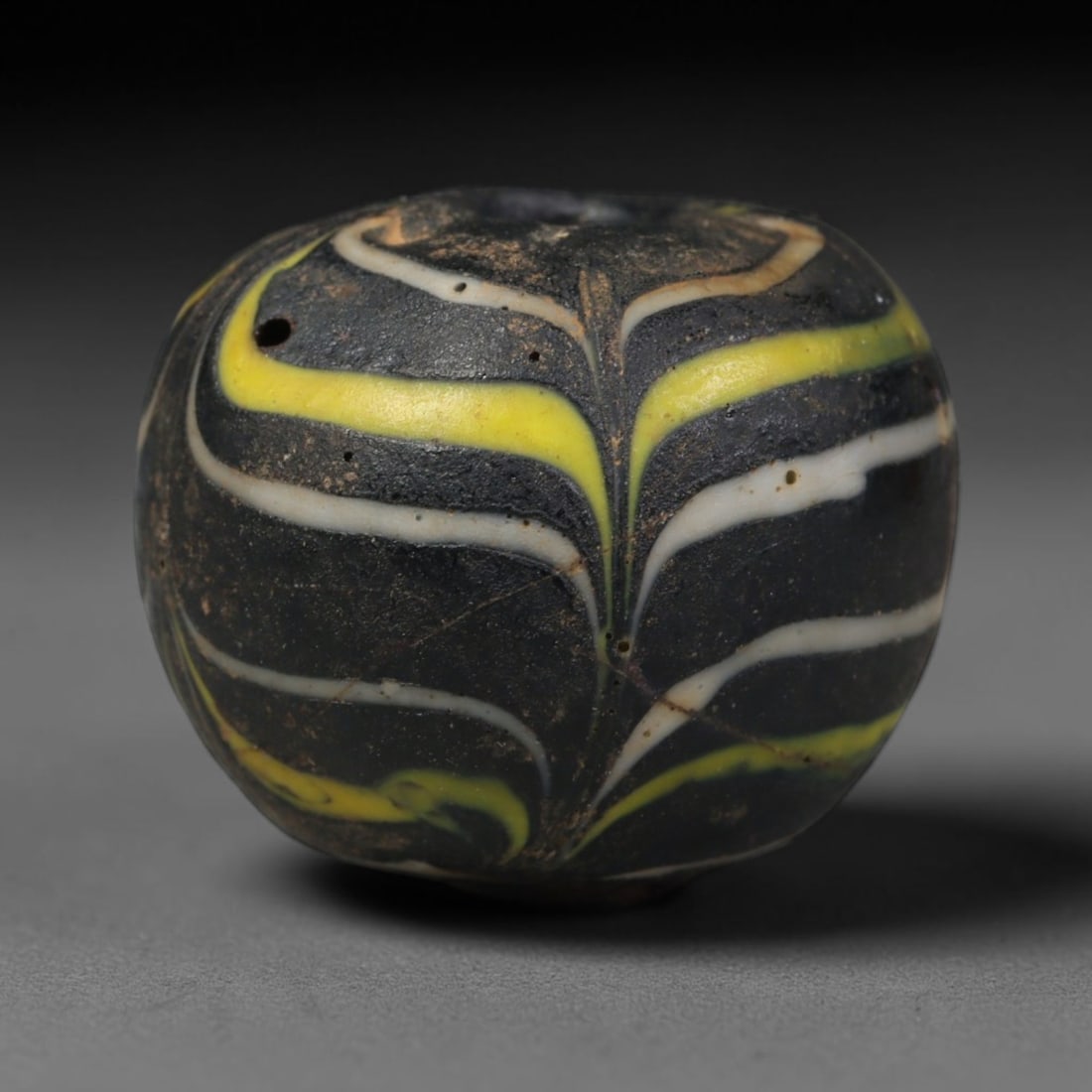 Ancient Islamic Hand Crafted Glass Bead Talisman, 46AC: Miniature antique wearable bead formed from hand-worked glass material, originating from ancient Islamic period glassmaking traditions across the Near East and North African cultural spheres. Glass wa
