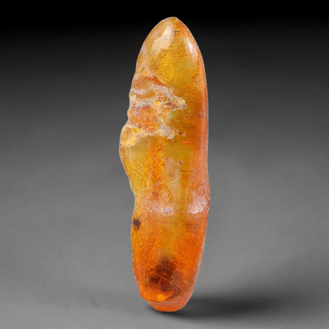 19.70ct Natural Baltic Polished Loose Freeform Amber Gemstone, 22EB: This smoothly polished freeform amber piece carries warm translucent organic clarity with fine natural fossil flecks and tiny mineral inclusions suspended throughout its 53x16mm flowing unstructured s