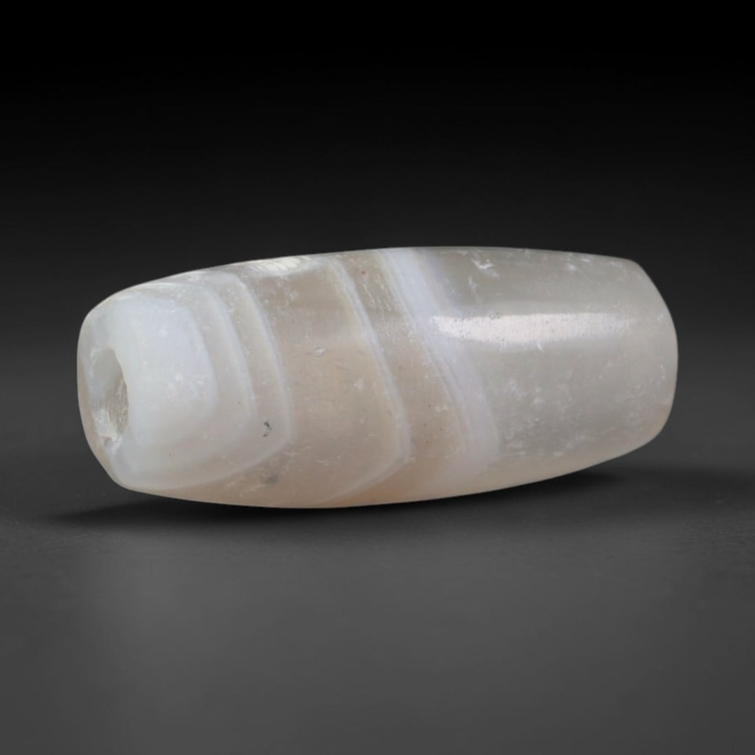 Ancient Elamite Civilization Banded Agate Barrel Bead (3200-539 BCE), 15AD: This antique banded agate barrel bead originates from the Elamite Civilization, an independent ancient Iranian culture that developed distinct agate bead craftsmanship and traded finished chalcedony p