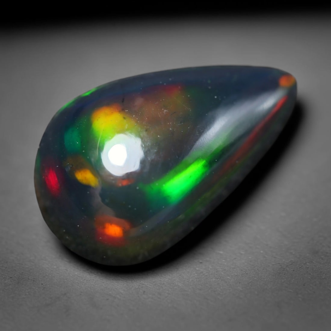 3.18ct Natural Ethiopian Welo Black Smoked Opal Cabochon Loose Gemstone, 20BY: This fully polished Ethiopian Welo opal features a dark smoked base with vivid, sweeping play-of-color shifting across its glossy dome surface, measured at 14x9x5mm. The black smoke treatment deepens 