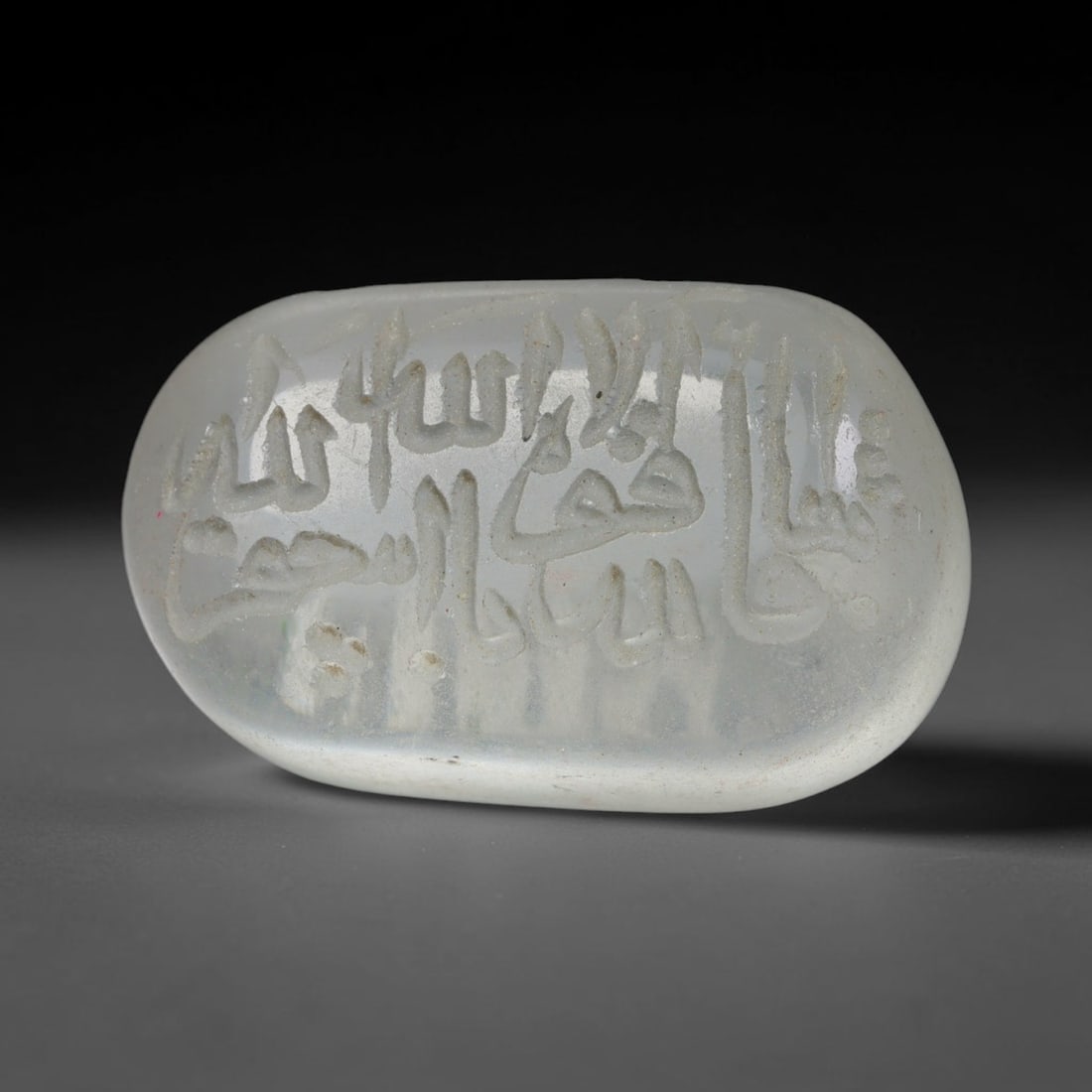 Early Vintage Islamic White Glass Calligraphic Intaglio Seal Cabochon (Post 1900 CE), 91BX: This early vintage glass intaglio seal cabochon draws from enduring Islamic seal-making traditions, formed from translucent pale glass with a smoothly rounded polished surface. The face features caref