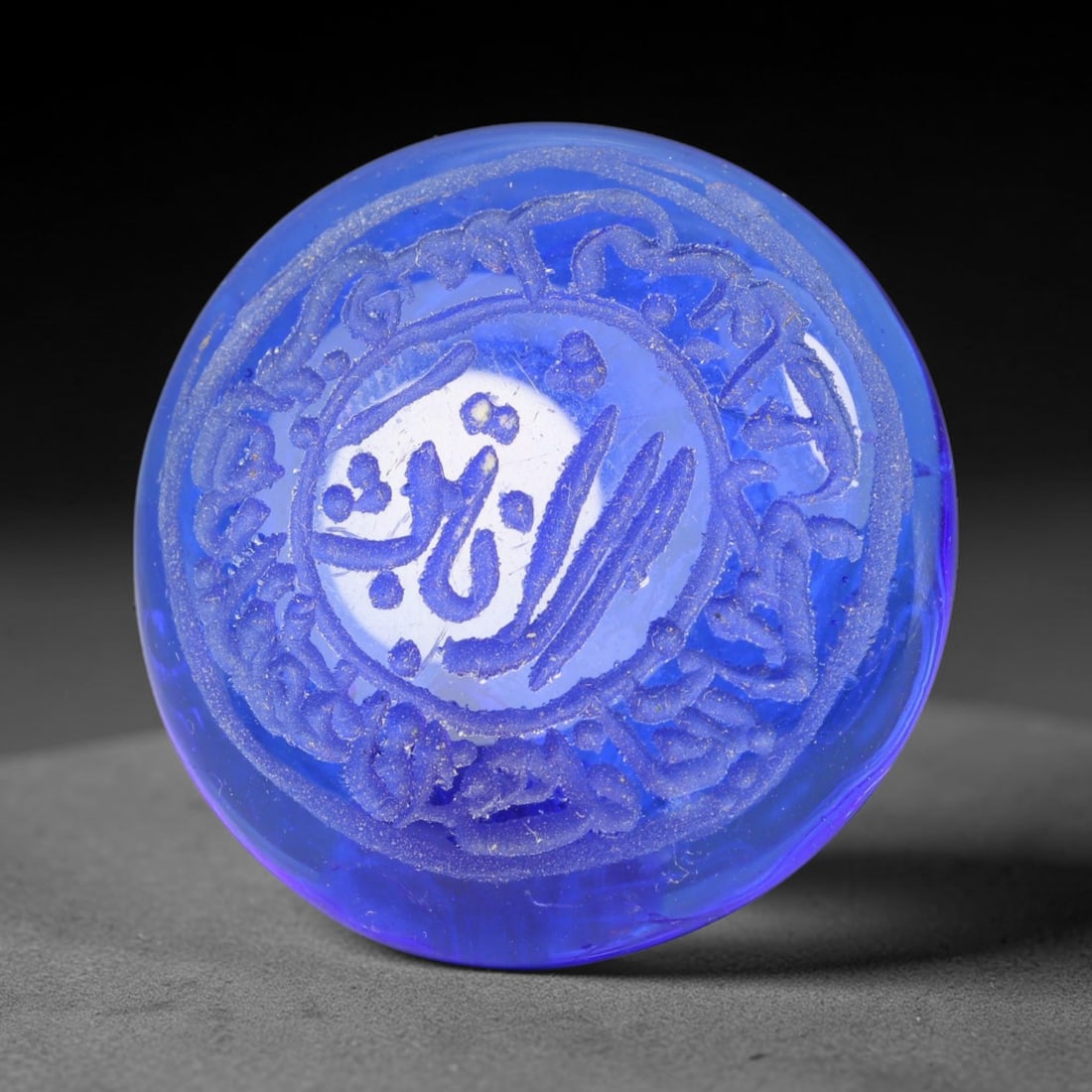 Early Vintage Islamic Cobalt Blue Glass Calligraphic Intaglio Seal Cabochon (Post 1900 CE), 92BX: This early vintage glass intaglio seal cabochon follows traditional Islamic lapidary and seal-making heritage, crafted from rich translucent blue glass. Its polished domed surface bears deeply moulded
